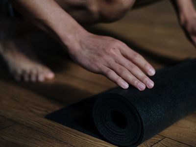 Roll of yoga mat on a dark wooden floor.